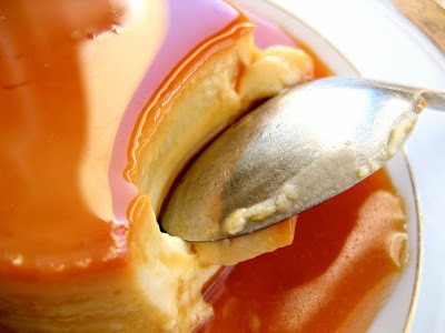spoon cutting into creme caramel