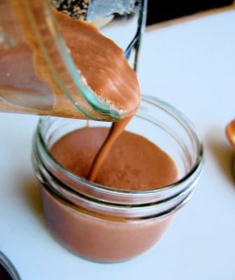 chocolate pudding being poured into a glass bowl
