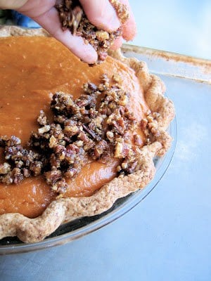 pecans being sprinkled onto pie