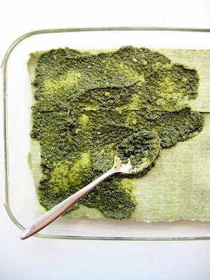 pesto being spread onto lasagna layer 