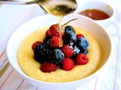 honey being poured onto berries and grits