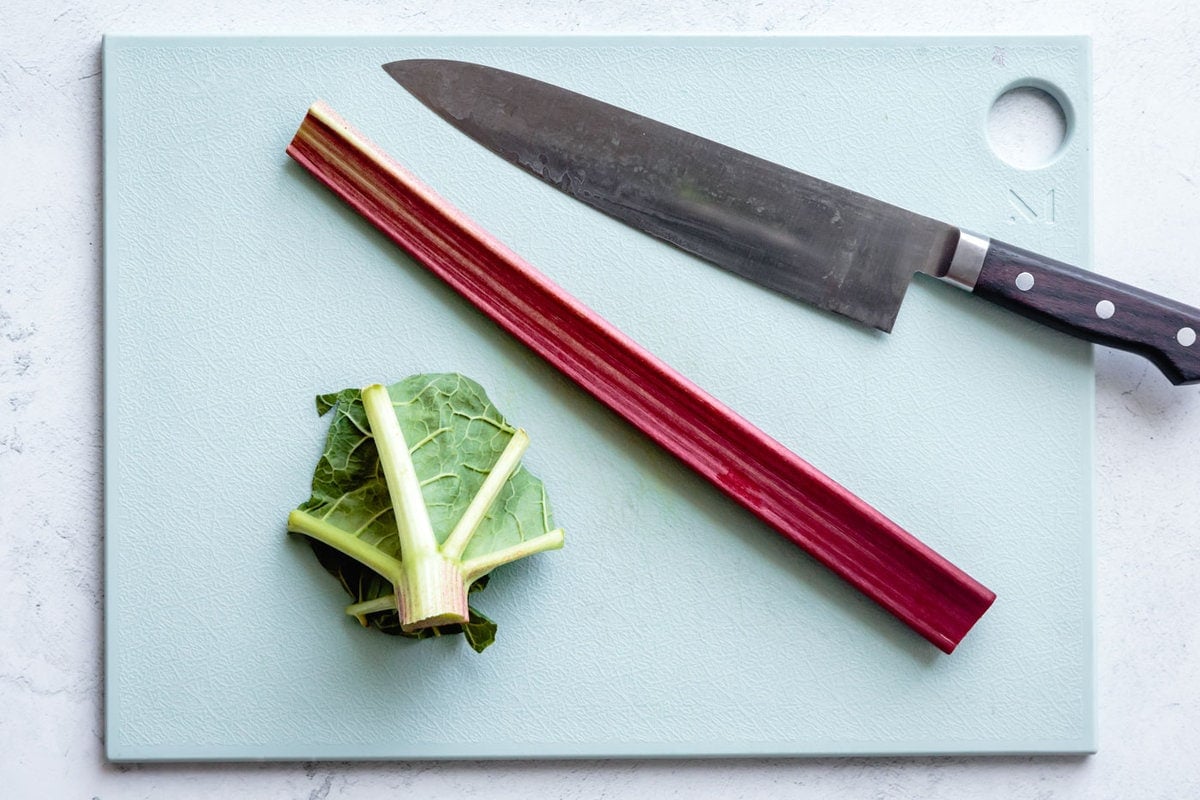 the leaf has been removed from a stalk of re rhubarb on a blue cutting board