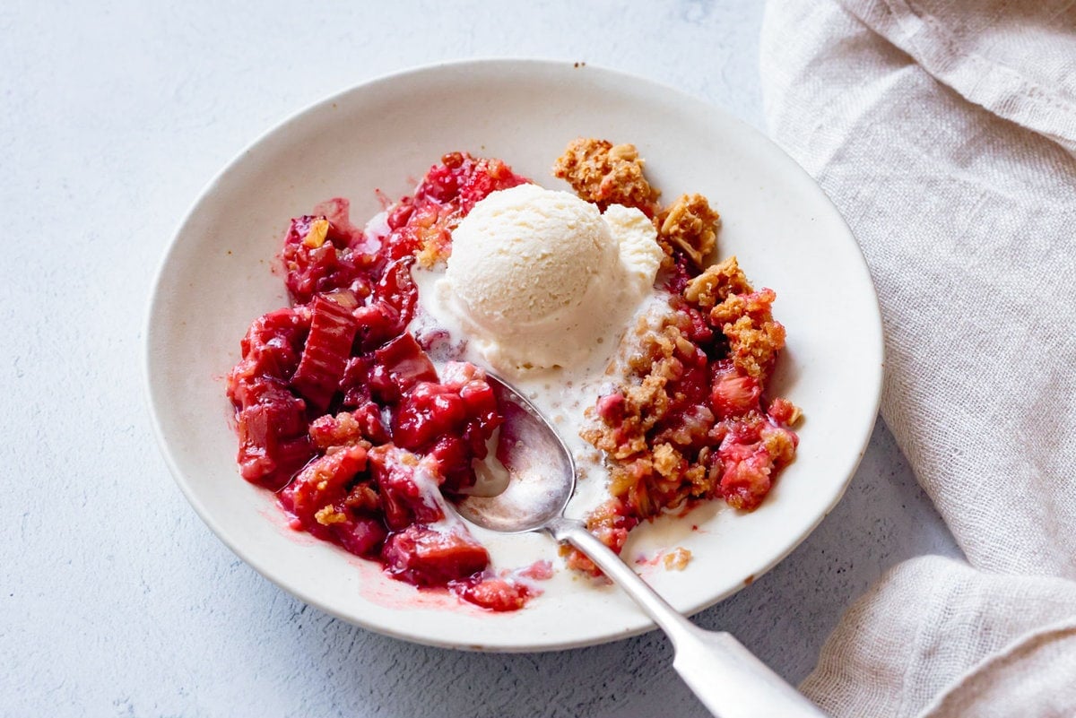 crisp has been scooped into a bowl and topped with a scoop of ivory-colored ice cream