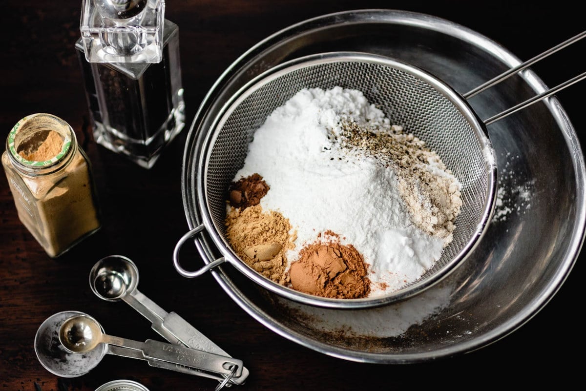 Dry ingredients for the molasses cookies are in a strainer ready to be sifted