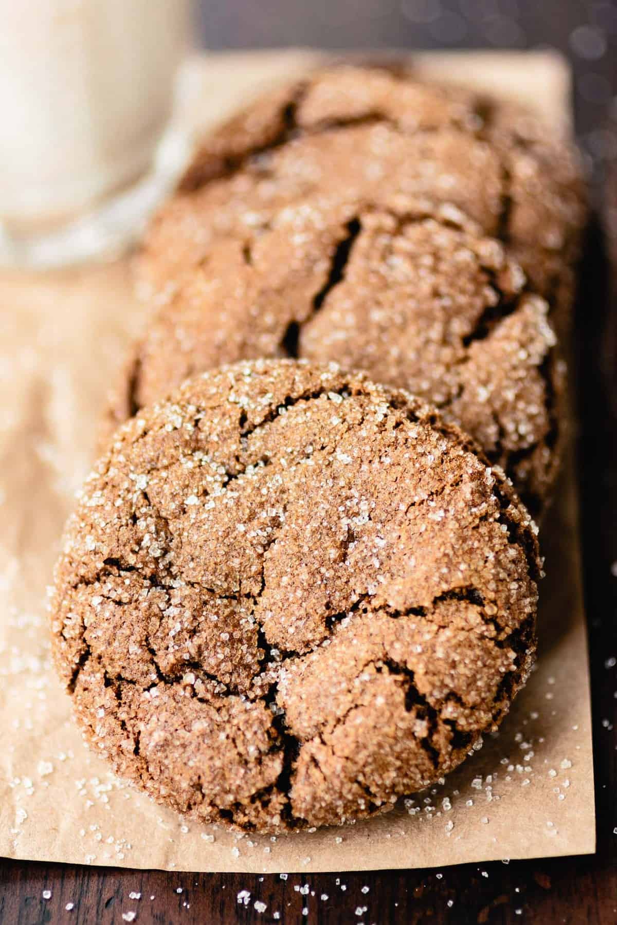 A close-up shot of a gluten-free ginger molasses cookie shows the pillowy top and sugar crusted crinkles