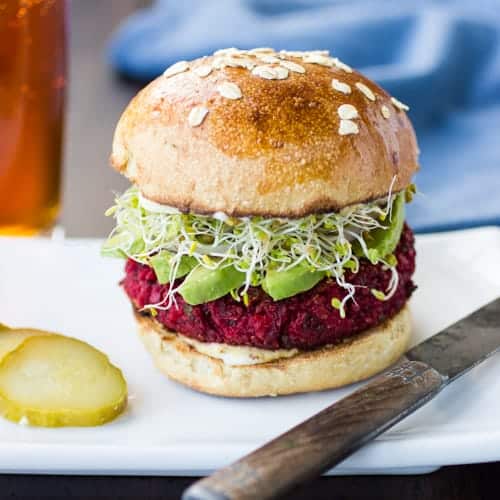 quinoa beets and chickpea burger on a plate with a pickle slice 