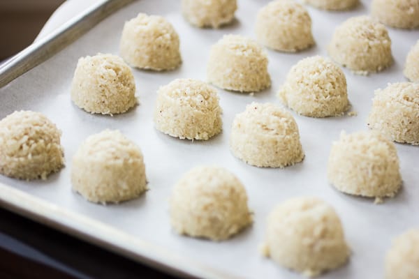 macaroon batter is scooped onto a baking sheet in mounds
