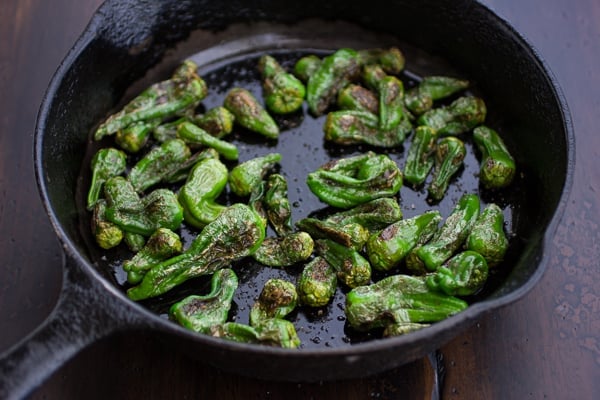 padron peppers cooking in a skillet 