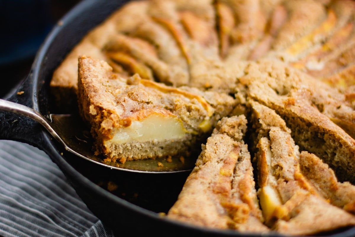 a slice of gluten-free pear cake is being lifted out of the skillet