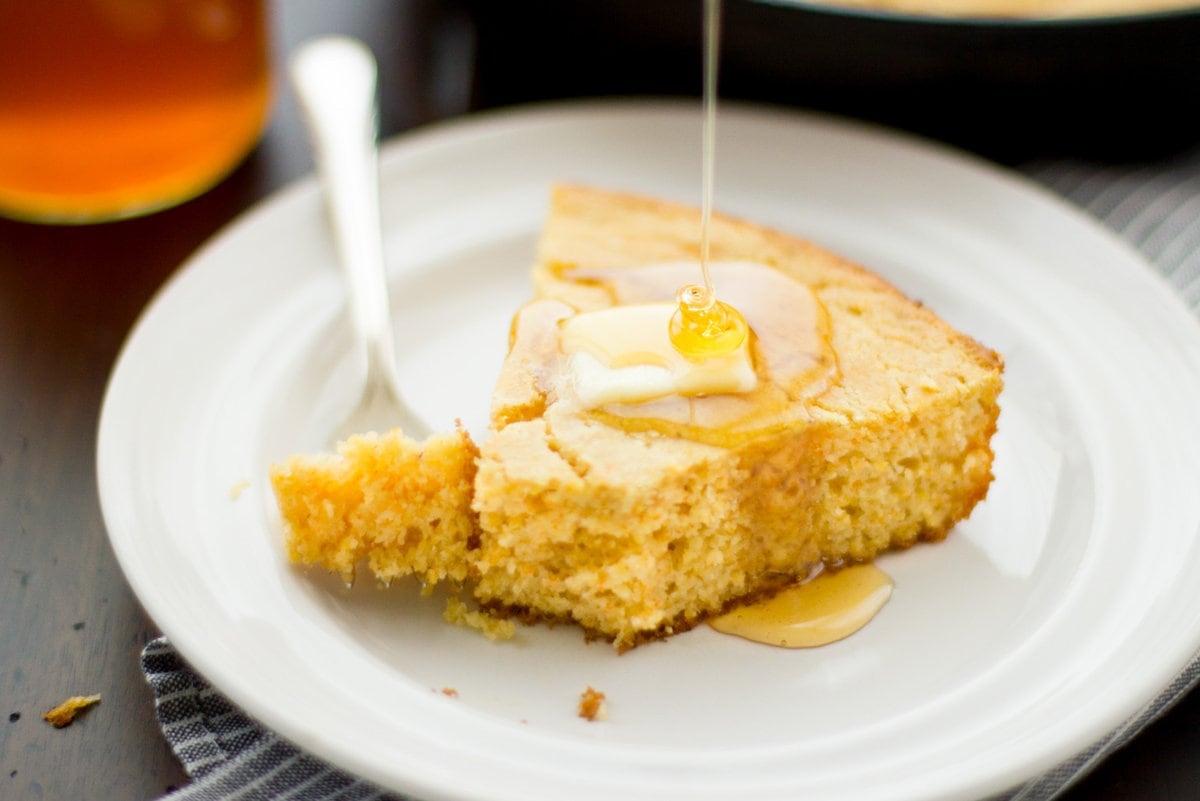 a slice of cornbread is topped with butter and a honey drizzle