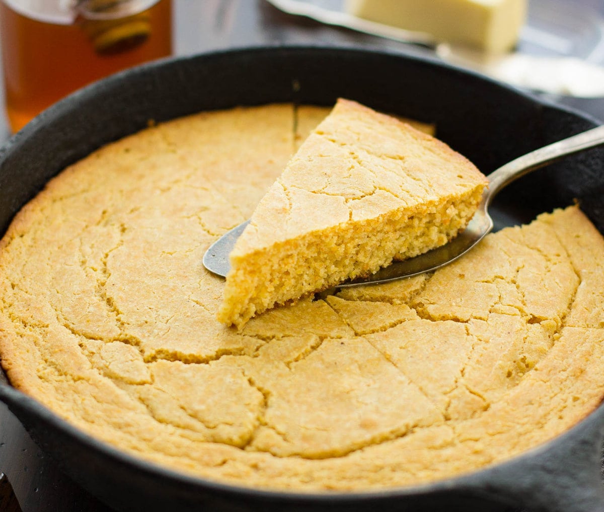 a wedge of cornbread has been cut out of the pan showing its lovely texture