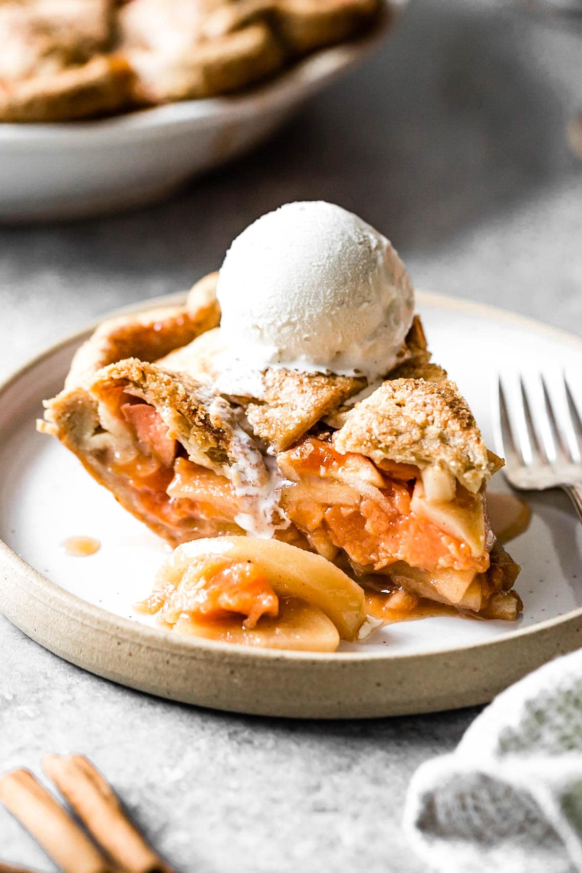 A tantalizing slice of pie stuffed with glossy fruit and a crispy crust is topped with a scoop of drippy ice cream
