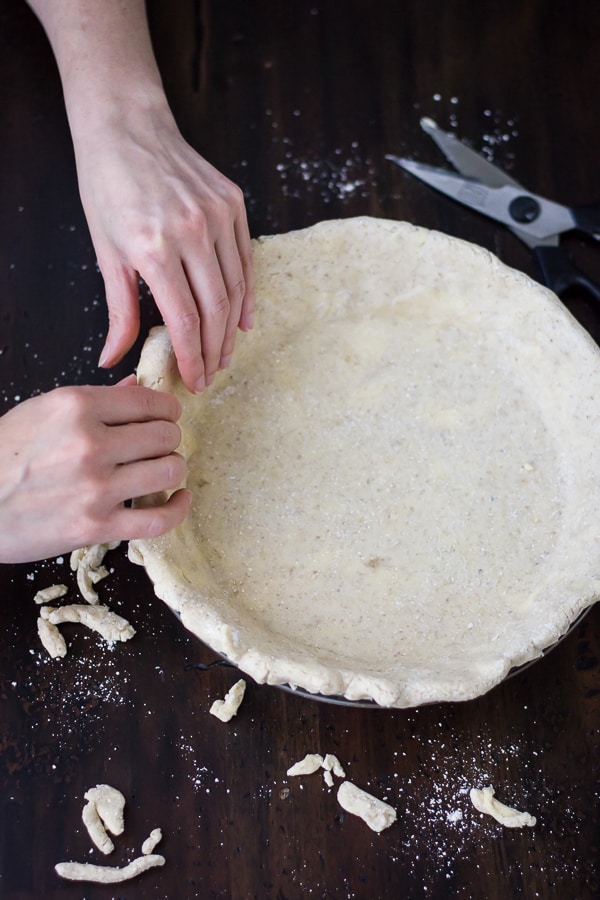 hands pressing Flaky Gluten-Free Pie Crust (Whole-Grain + Gum-Free) in a pan 