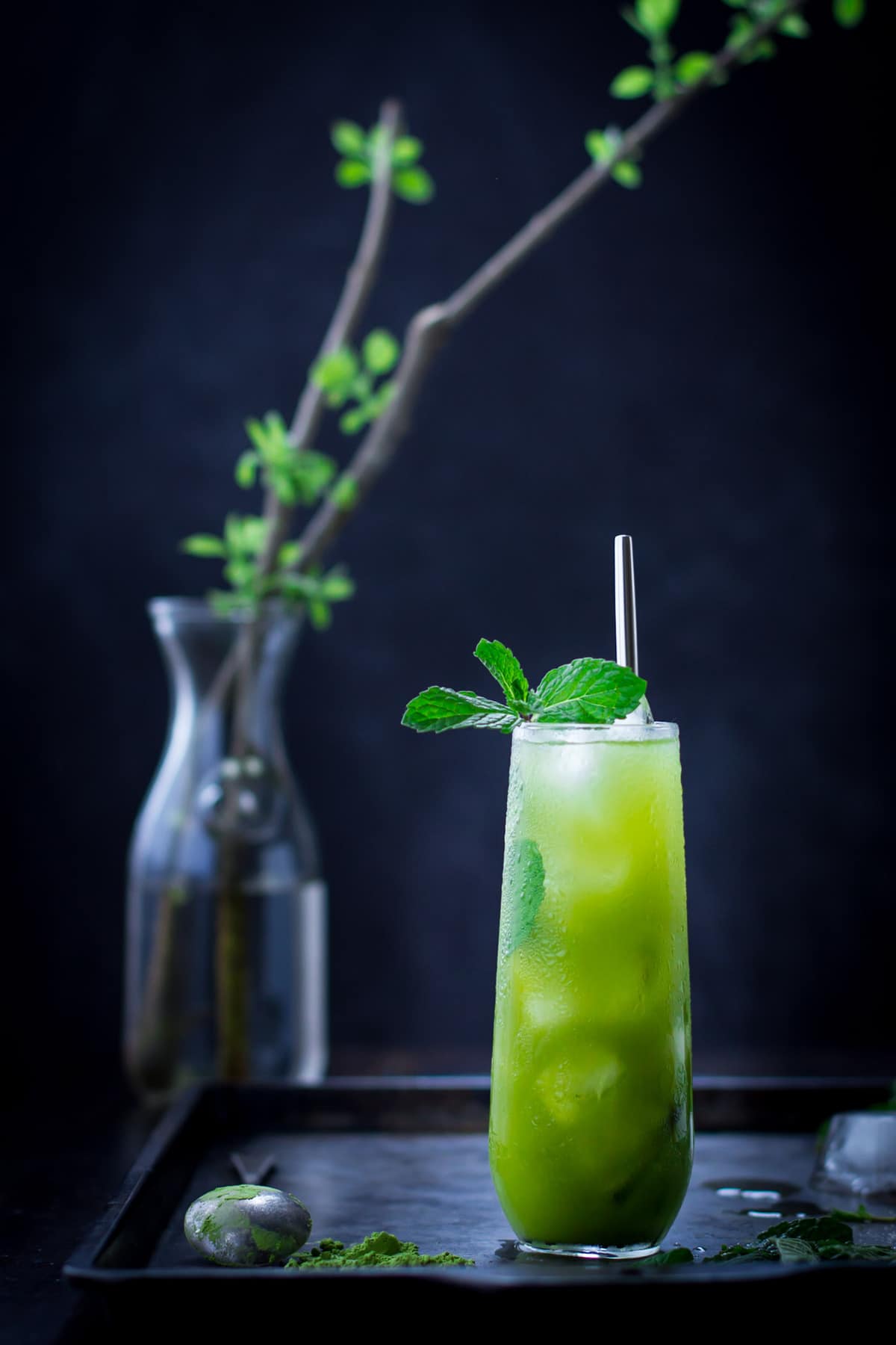 A bright green mint julep matcha cocktail in a highball glass with a green plant in the background