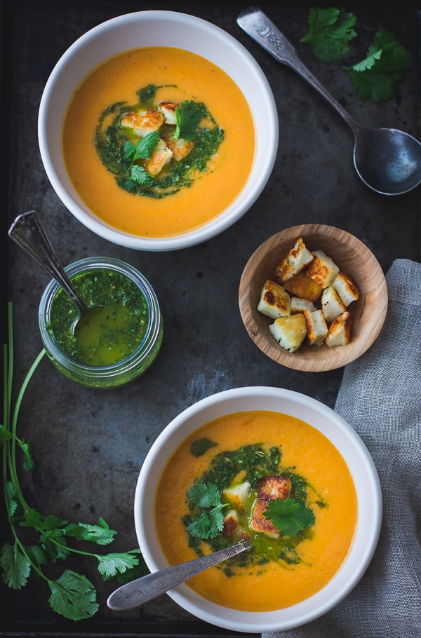 bowls of Roasted Yellow Tomato Soup with Green Harissa + Halloumi Croutons