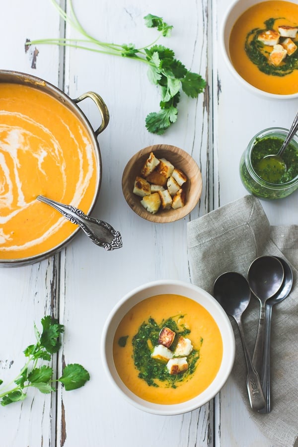 overhead shot of Roasted Yellow Tomato Soup with Green Harissa + Halloumi Croutons