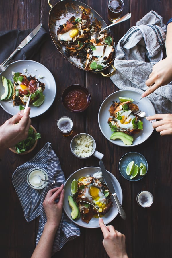 Baked Chilaquiles with Black Beans and Kale on table with hands