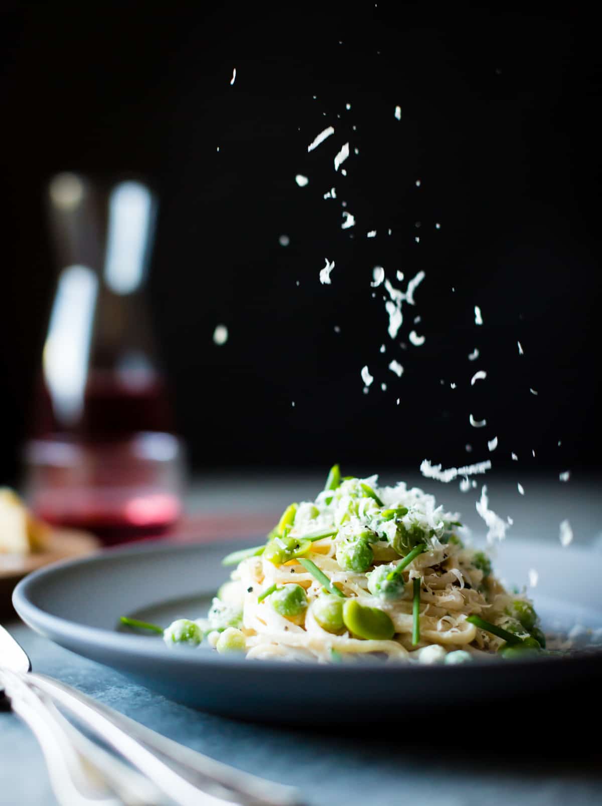 sprinkling cheese on Creamy Cashew-Miso Pasta with Peas and Fava Beans {gluten-free, vegan option}