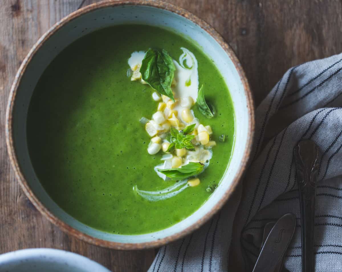 top down shot of Zucchini Basil Soup with Crème Fraîche and Pickled Corn