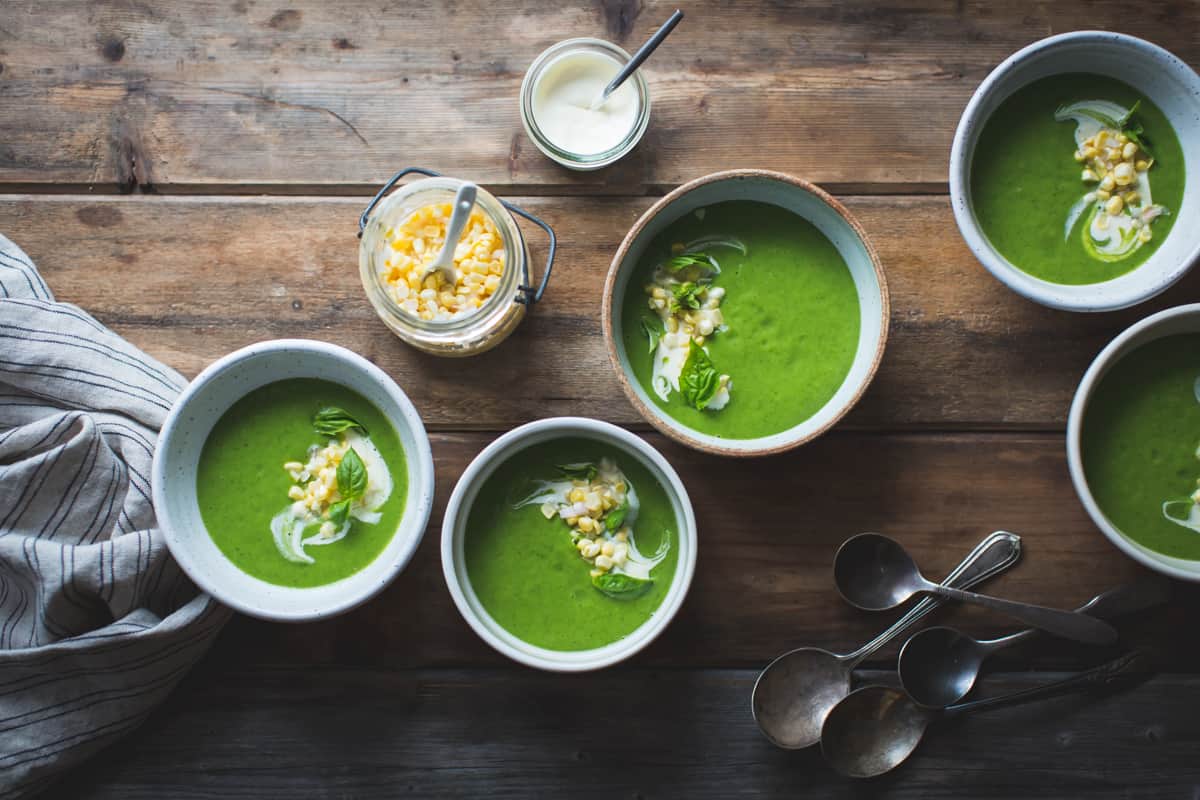 Zucchini Basil Soup with Crème Fraîche and Pickled Corn on table 