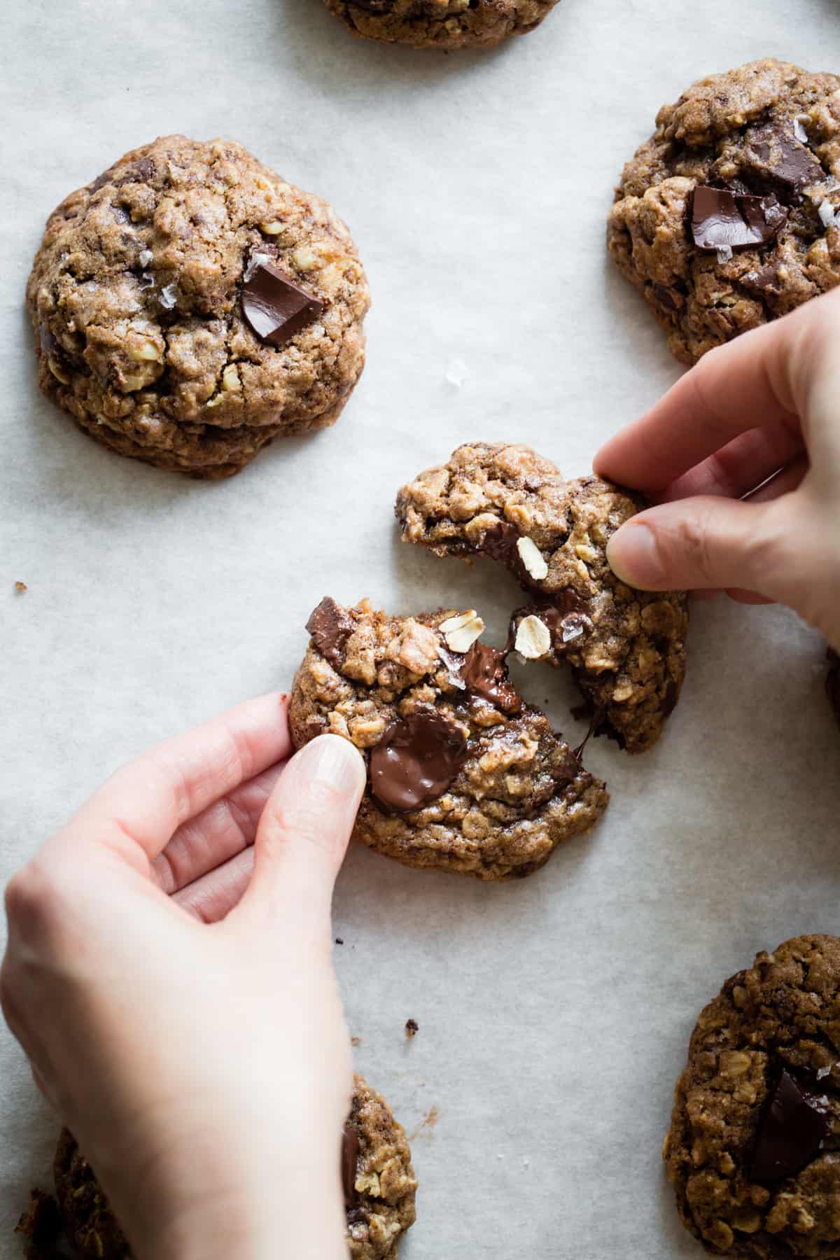 hands breaking Gluten-Free Oatmeal Teff Chocolate Chip Cookie