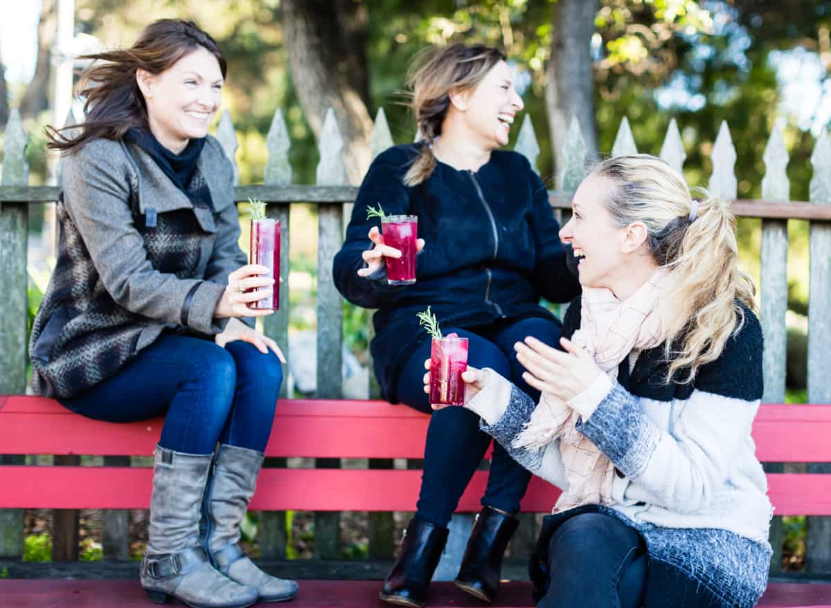 three friends holding glasses of Rosemary, Pomegranate, & Grilled Meyer Lemon Vodka Sparklers