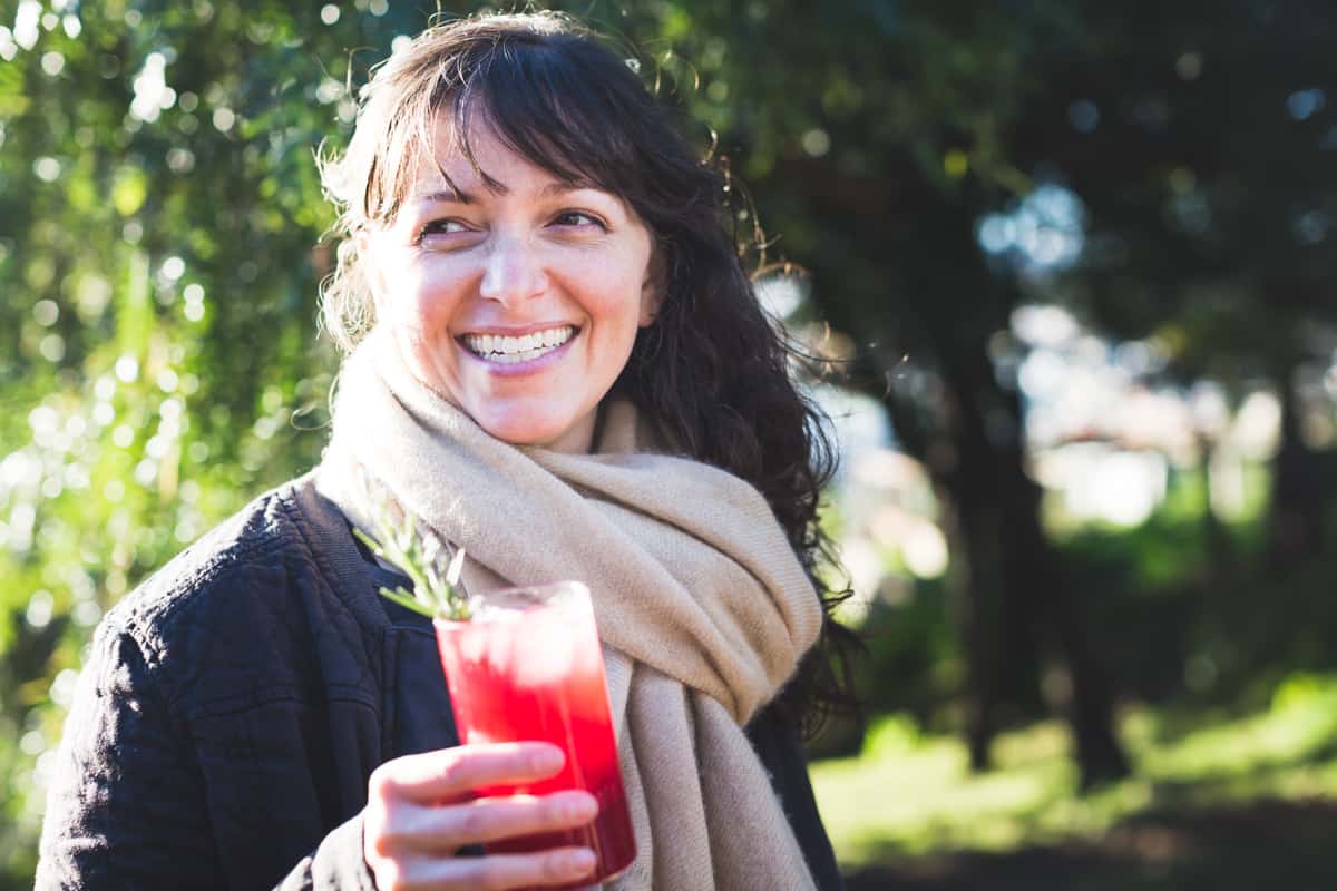 person holding a glass of Rosemary, Pomegranate, & Grilled Meyer Lemon Vodka Sparklers