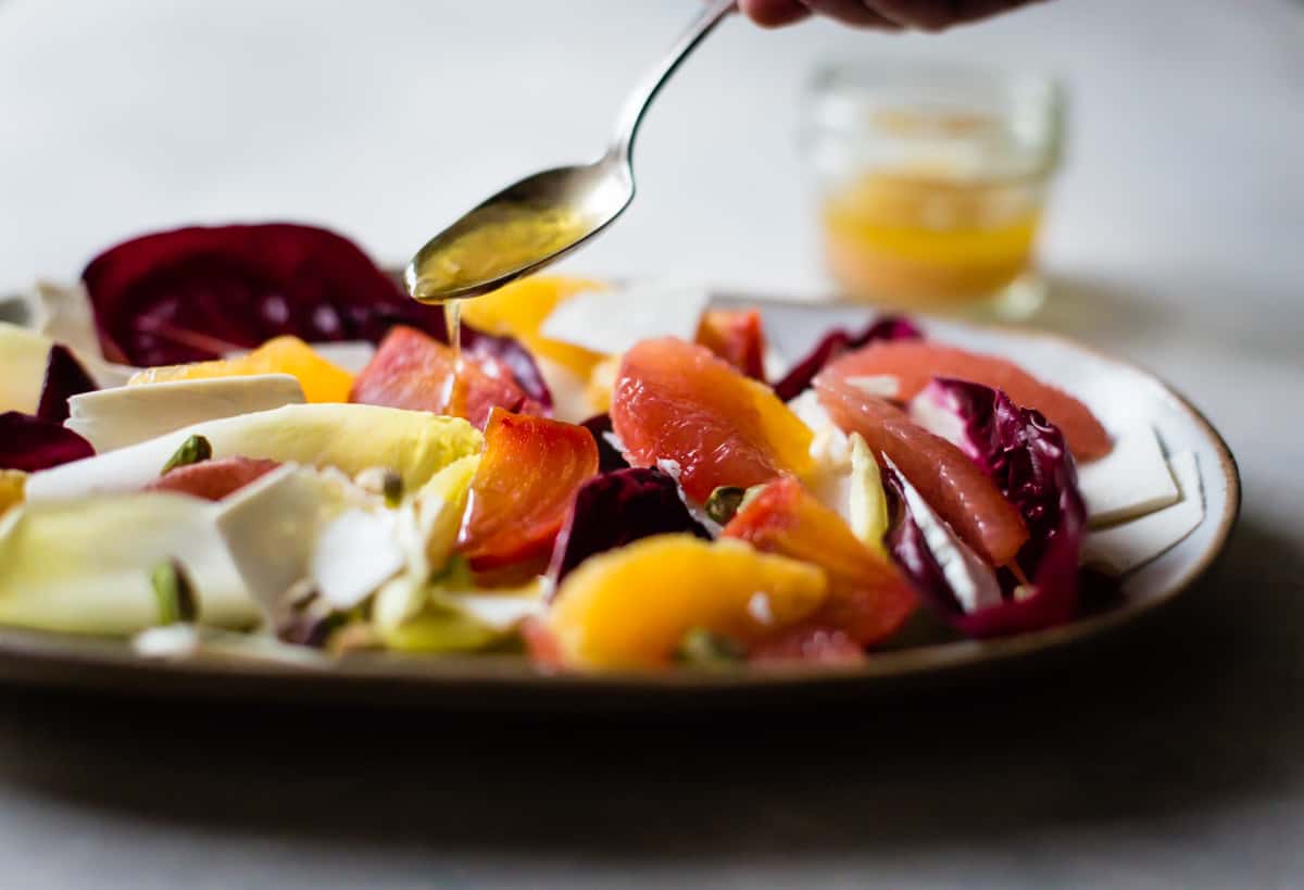 drizzling dressing on Beet, Citrus, & Chicory Salad with Ricotta Salata and Pistachios