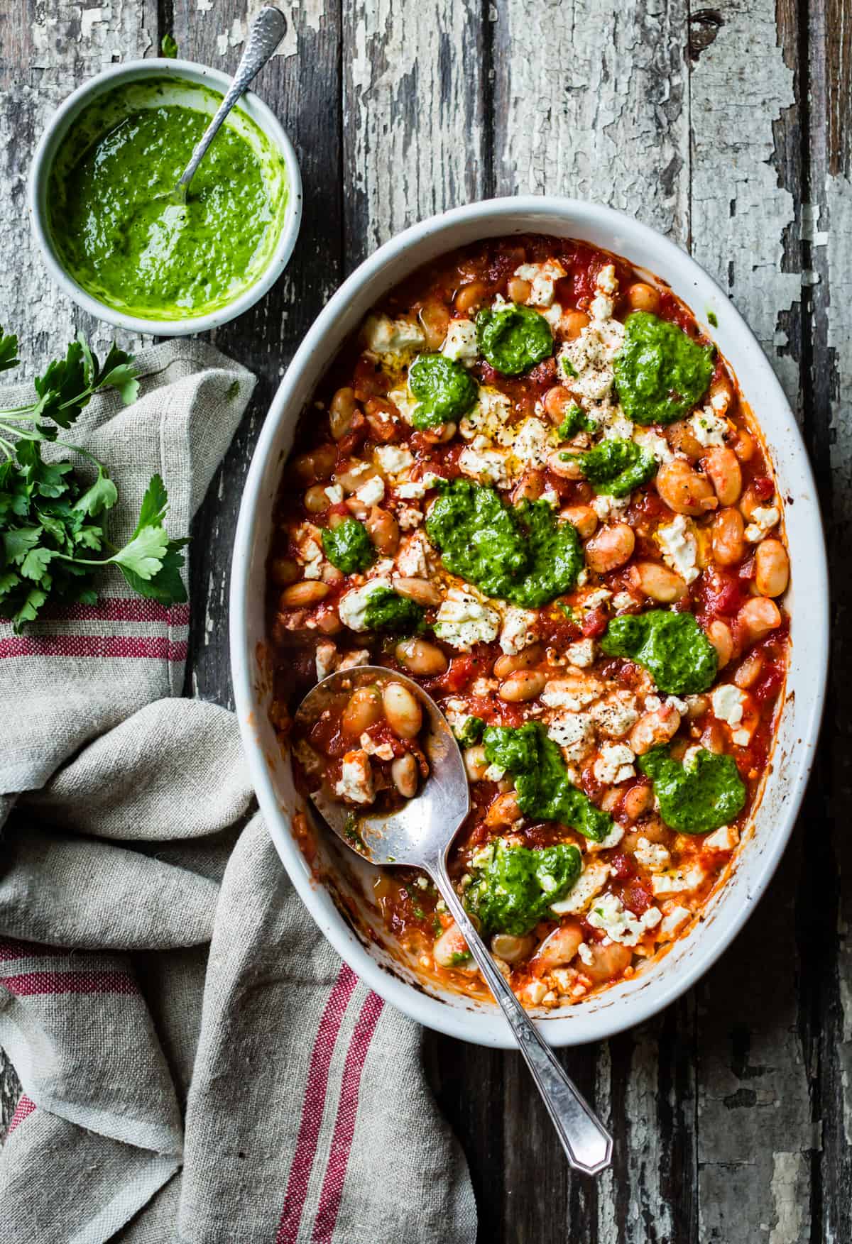 dish of Tomato Baked White Beans with Feta and Lemon Parsley Oil with spoon 