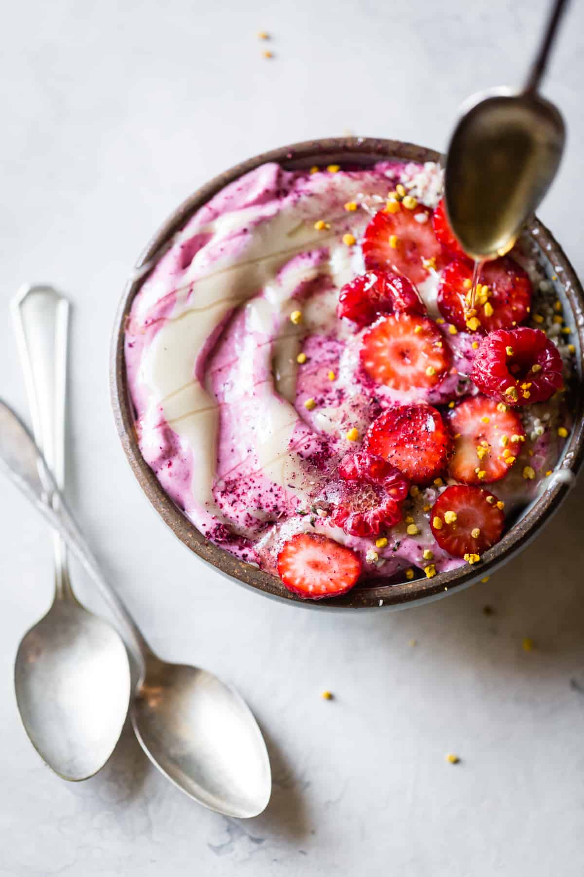 drizzling honey on Hibiscus Berry Smoothie Bowls