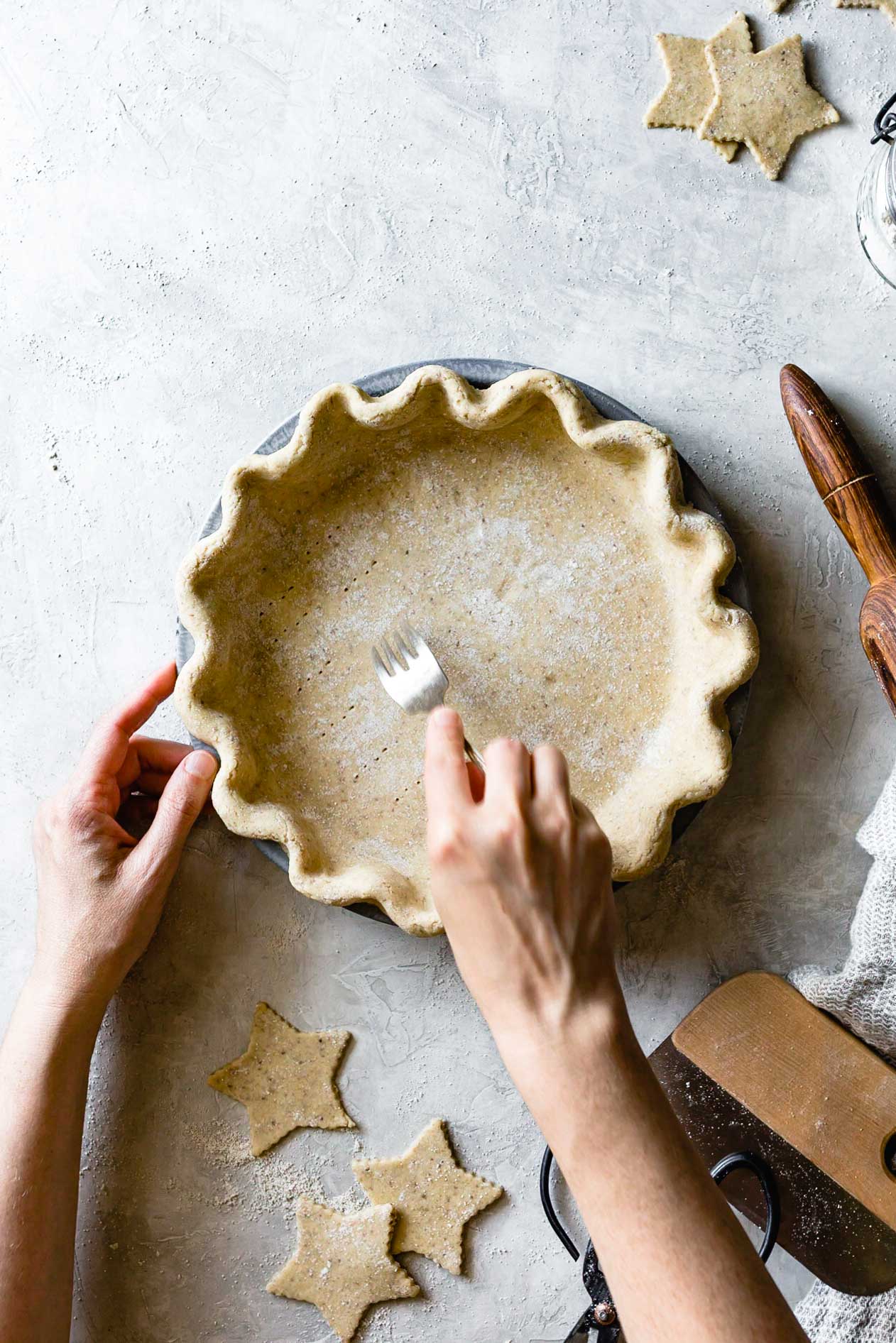 hands are pricking an unbaked gluten-free pie crust with a fork