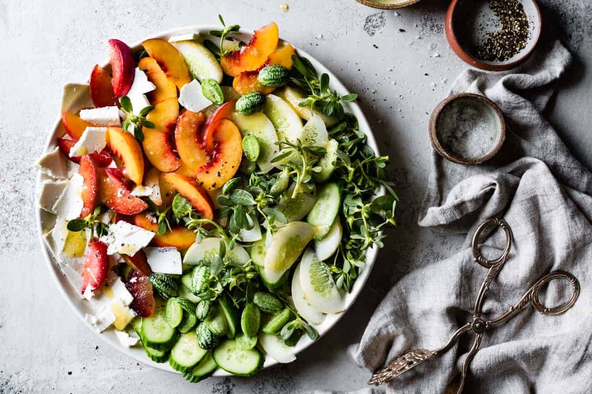 big plate of Stone Fruit Cucumber Salad with Ricotta Salata, Purslane, and Golden Balsamic Miso Vinaigrette