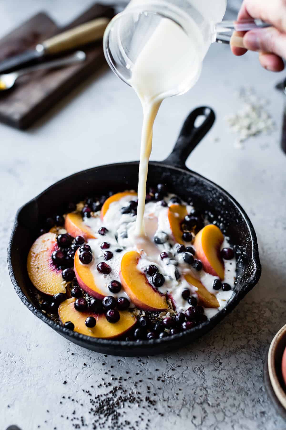 pouring milk on Super Seedy Vegan Baked Oatmeal with Peaches and Huckleberries {gluten-free & dairy-free}