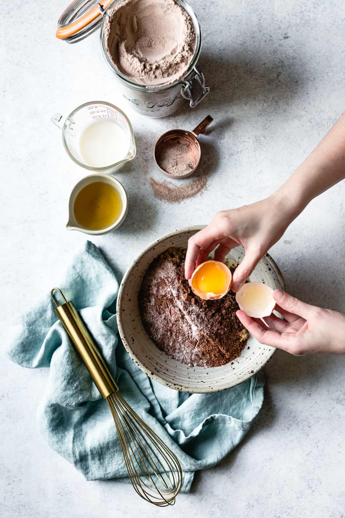 hands are cracking an egg into the bowl of dry ingredients