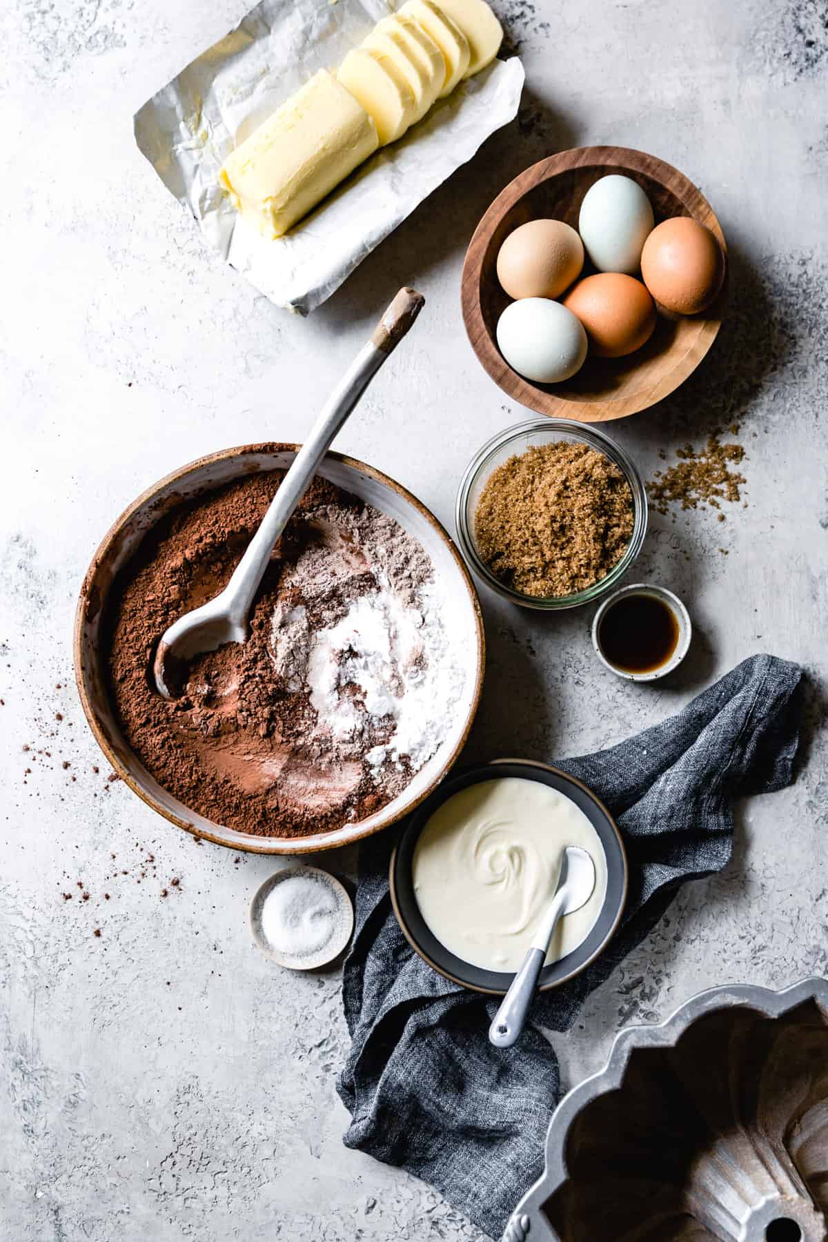 Ingredients for bundt cake have been arranged on a gray plaster surface