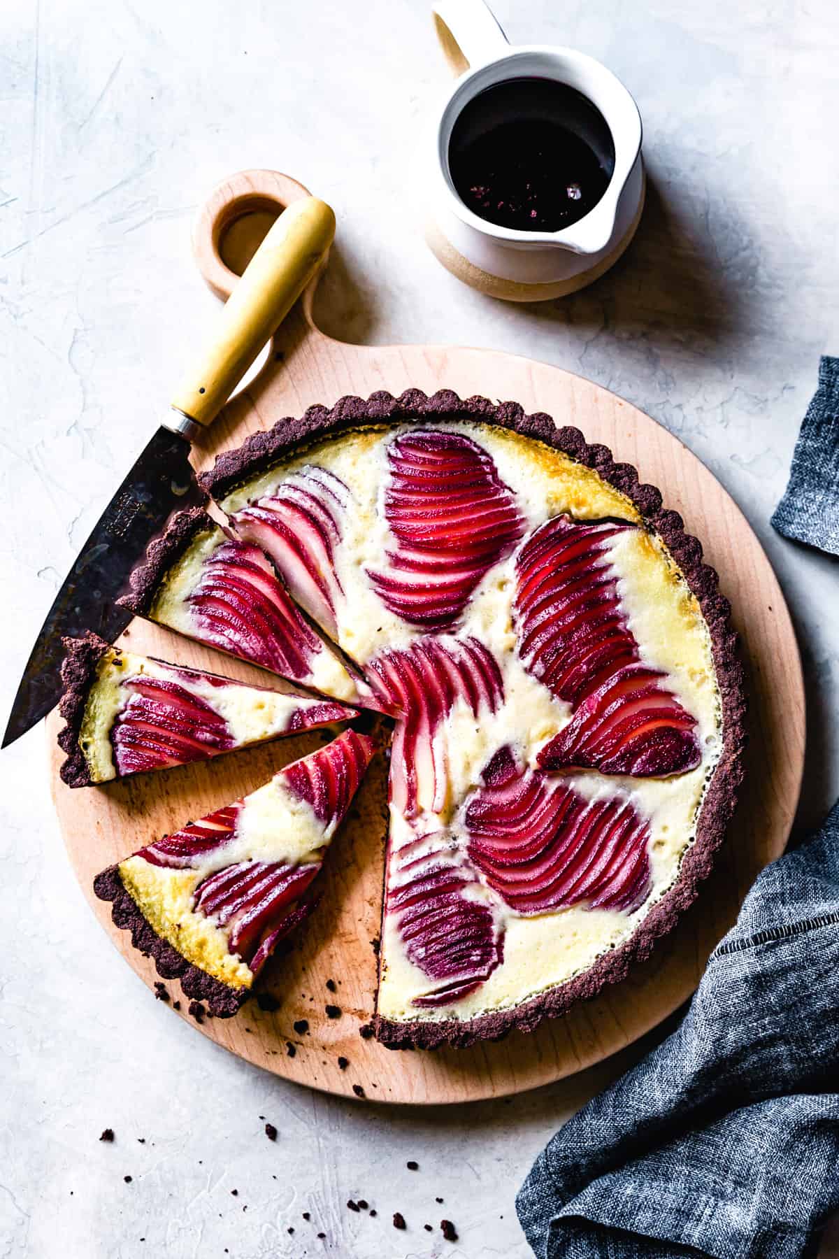 red wine poached pears have been baked into a tart with a chocolate crust and custard filling