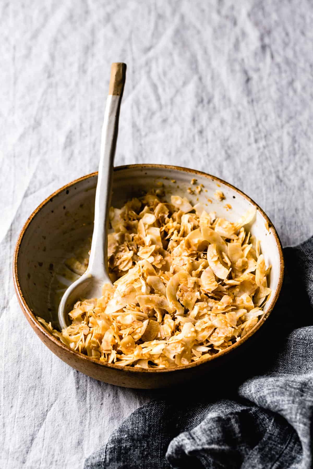 Coconut flakes have been mixed with the other ingredients in a stoneware bowl