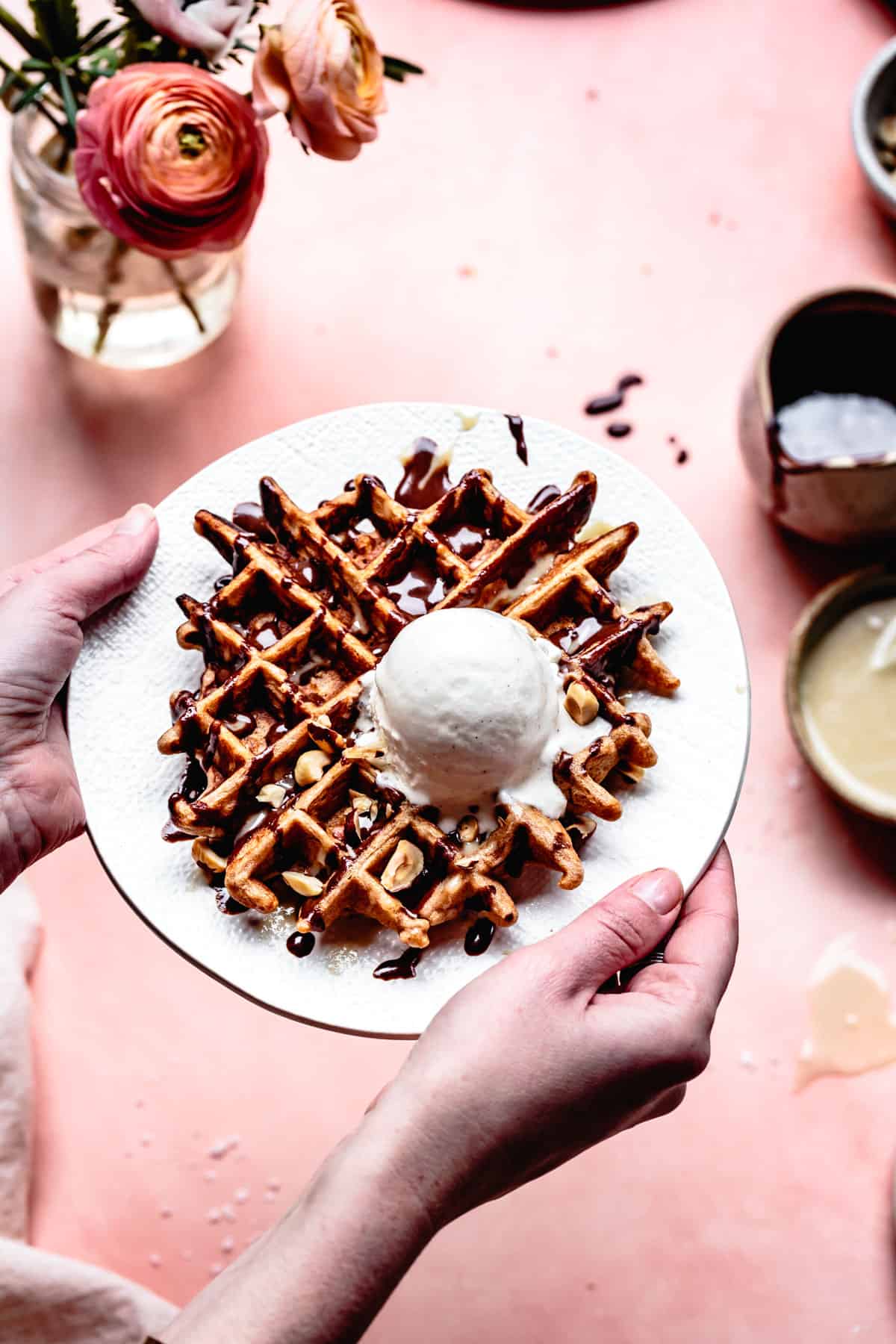 hands holding plate of waffles with Vegan Hot Fudge Sauce with Tahini {refined sugar-free}