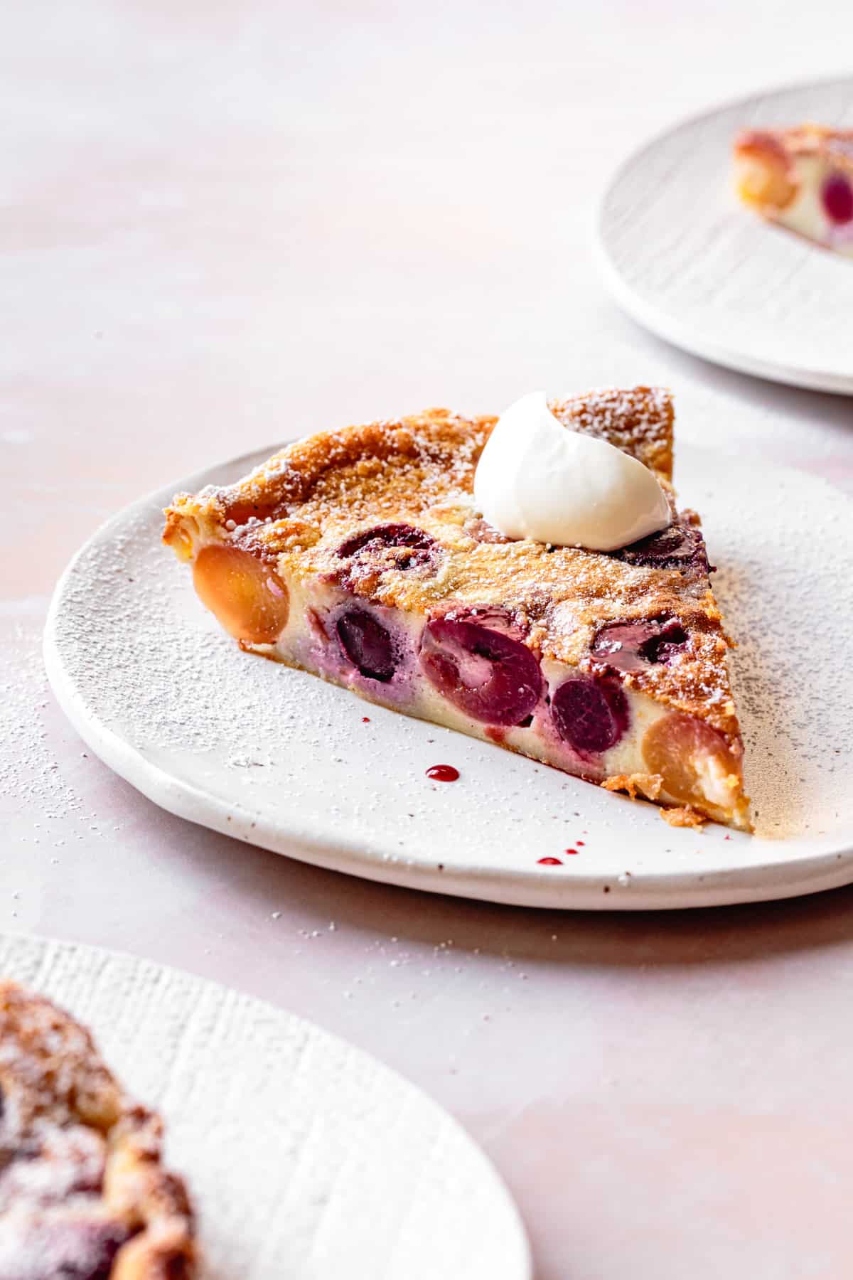 close up of Gluten-Free Cherry Clafoutis slice on a plate with creme fraiche