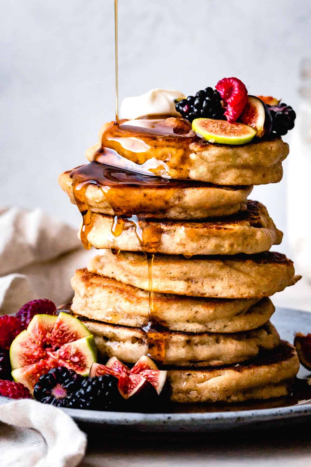 Stack of fluffy gluten-free pancakes with syrup and fruit