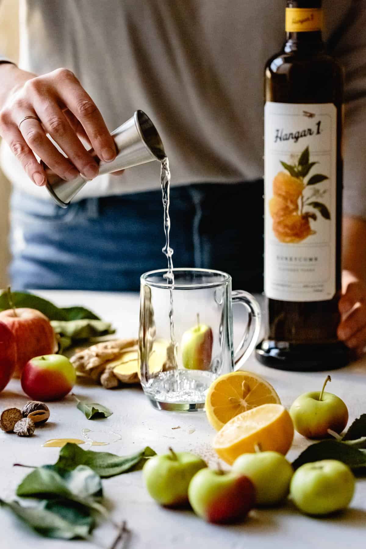 pouring vodka for apple cider hot toddy