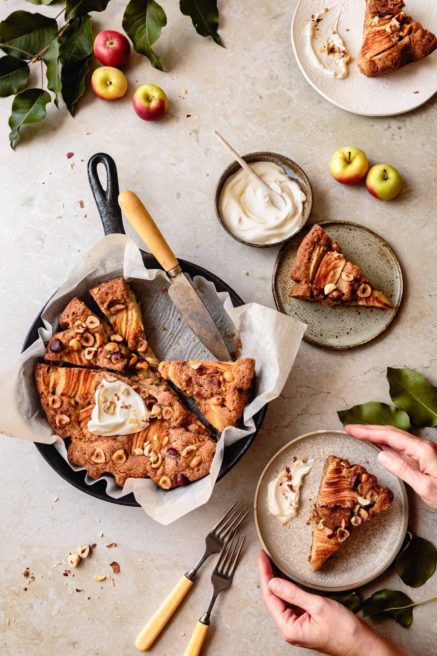 Serving slices of easy gluten-free apple cake with hazelnuts and creme fraiche