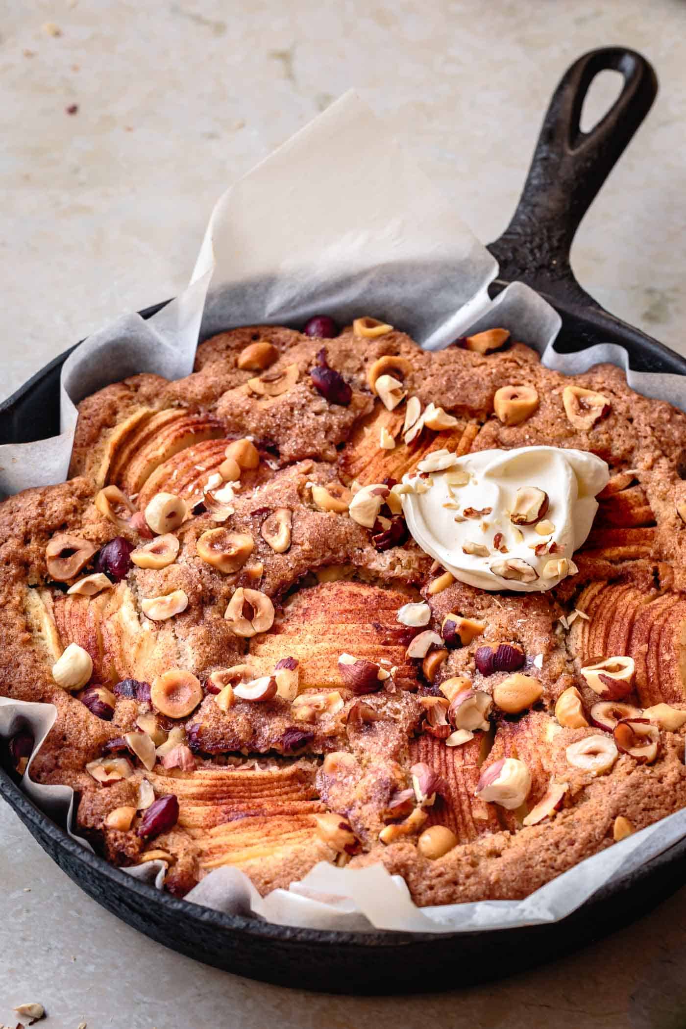 Gluten-free apple cake recipe in a skillet topped with creme fraiche