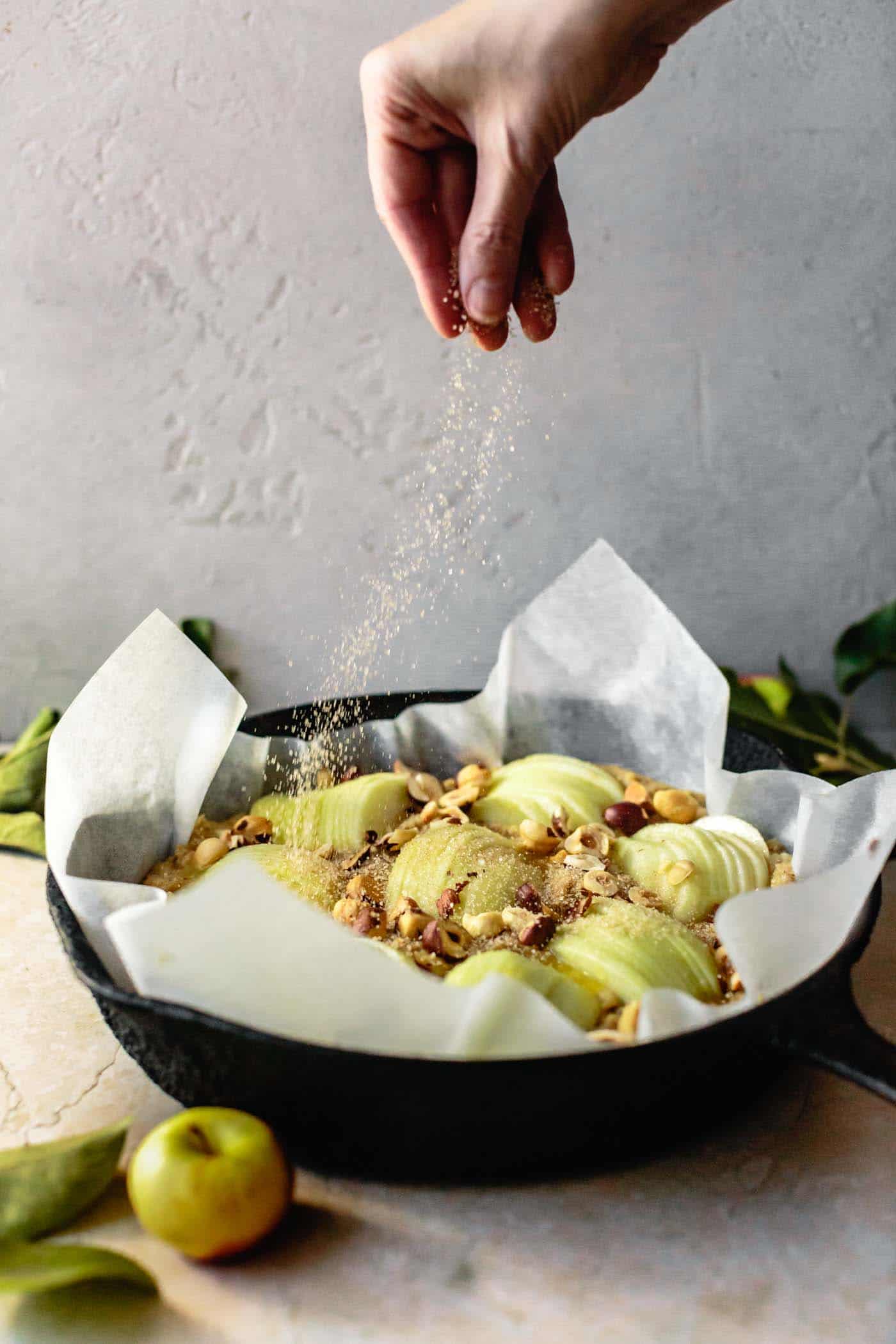 Sprinkling cinnamon sugar over gluten-free apple cake