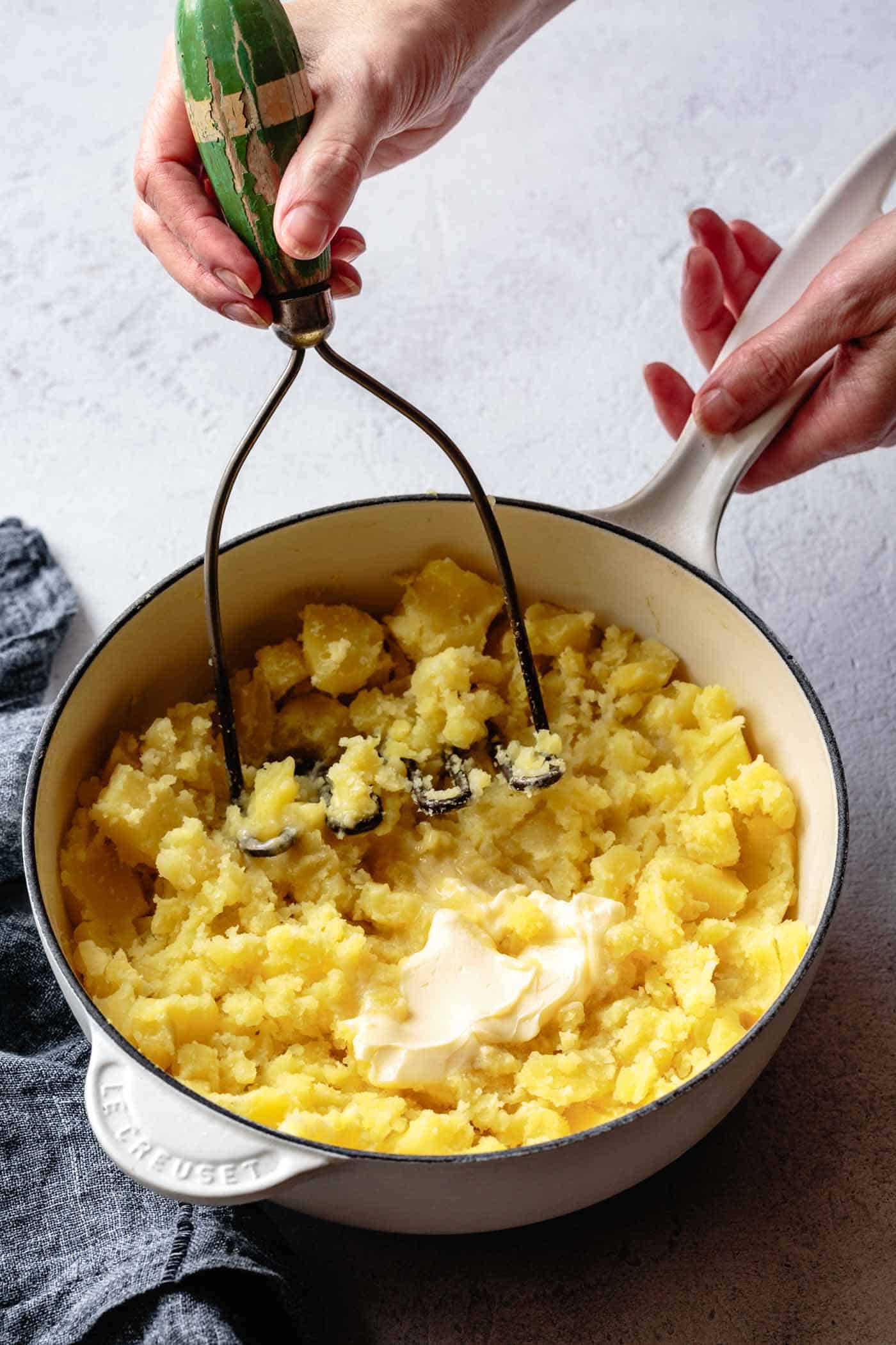 Mashing potatoes with butter in a pot