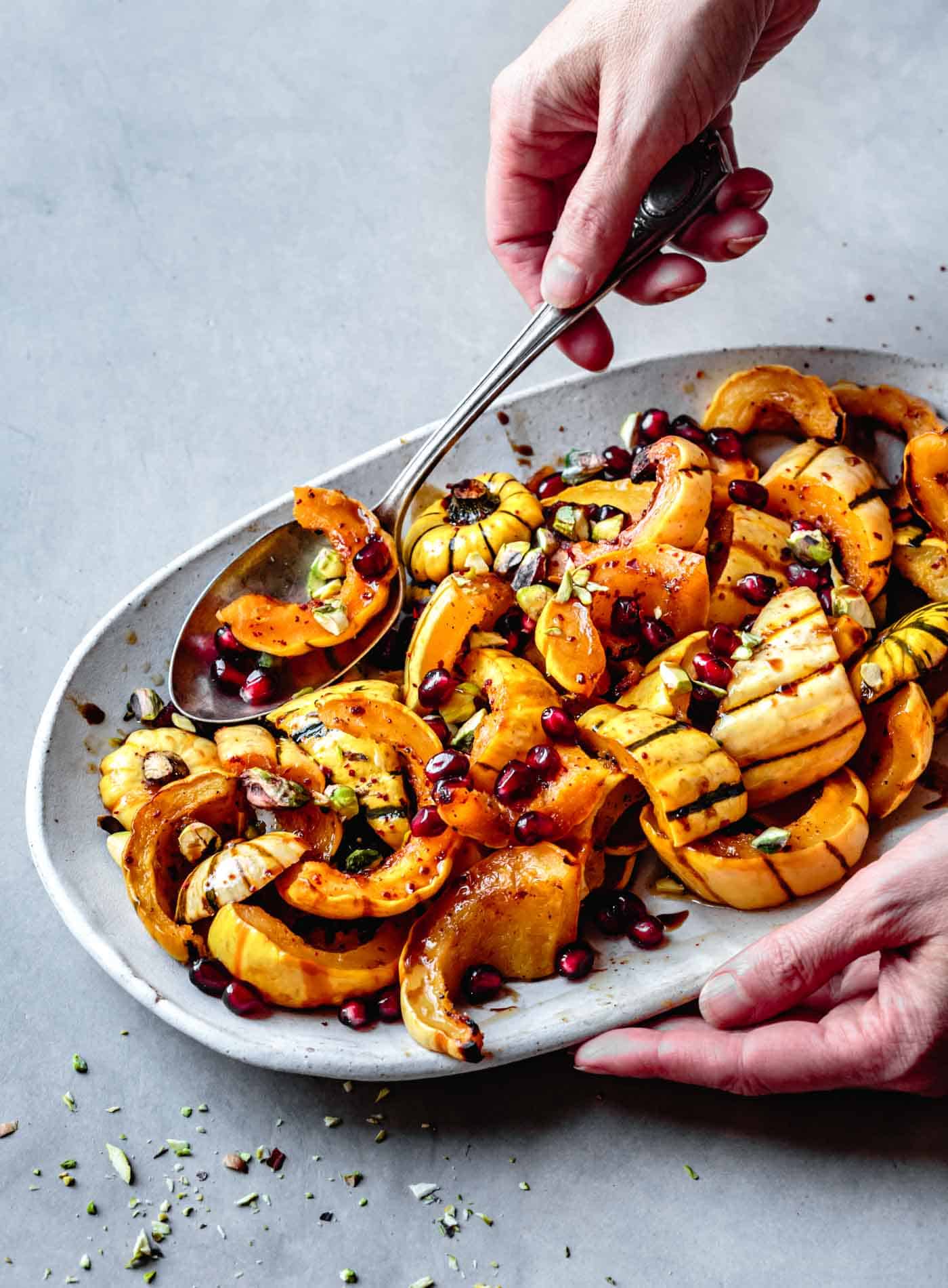 Serving roasted delicata squash with brown butter, pomegranate and pistachios