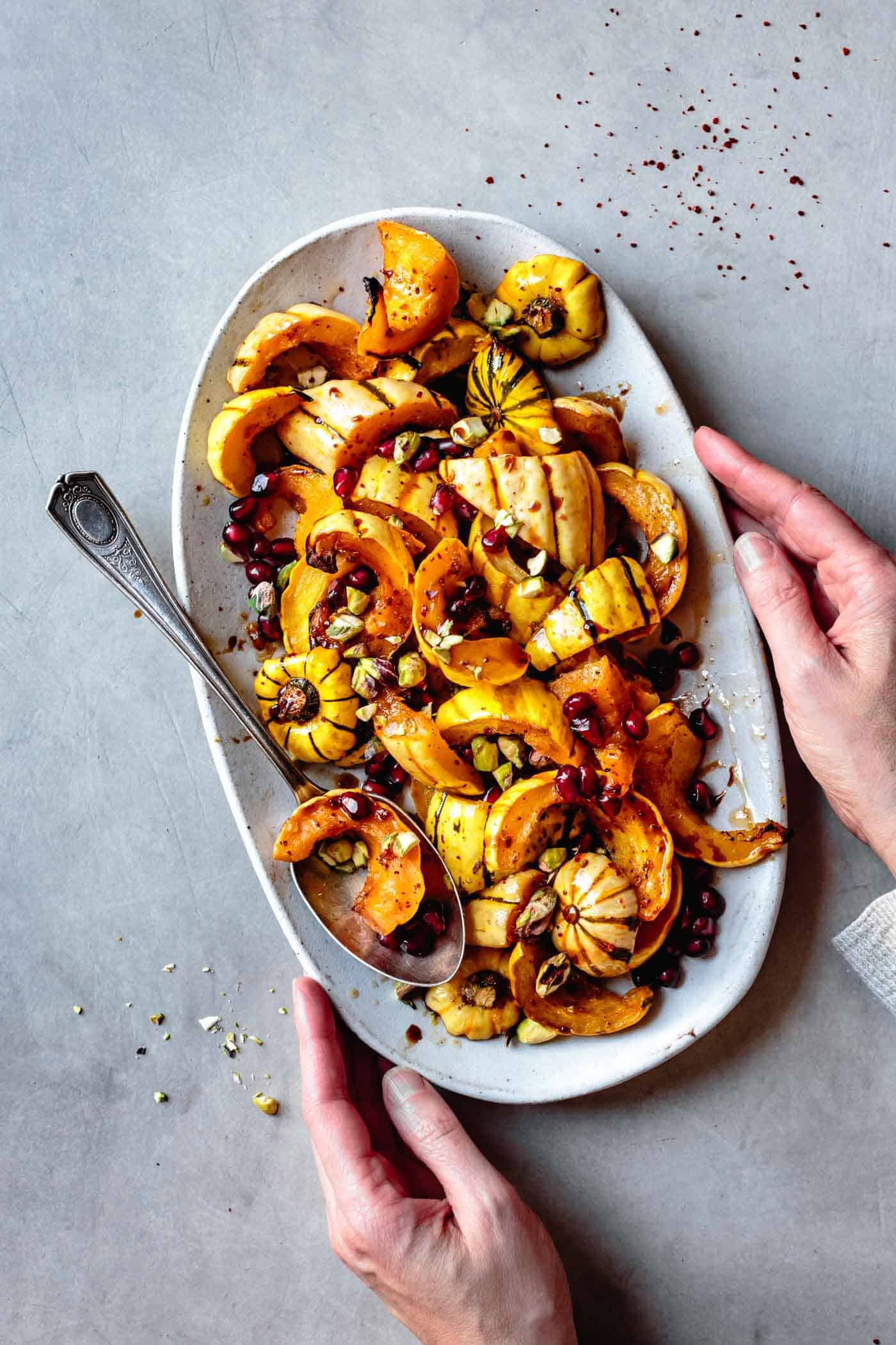 Roasted delicata squash being served on a platter