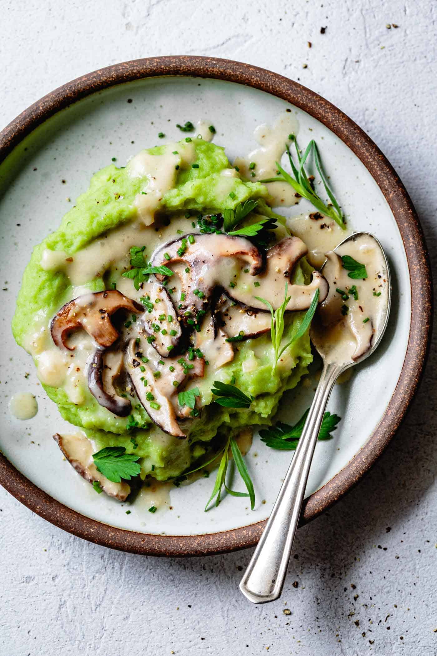 gluten-free mushroom gravy on a plate of green mashed potatoes