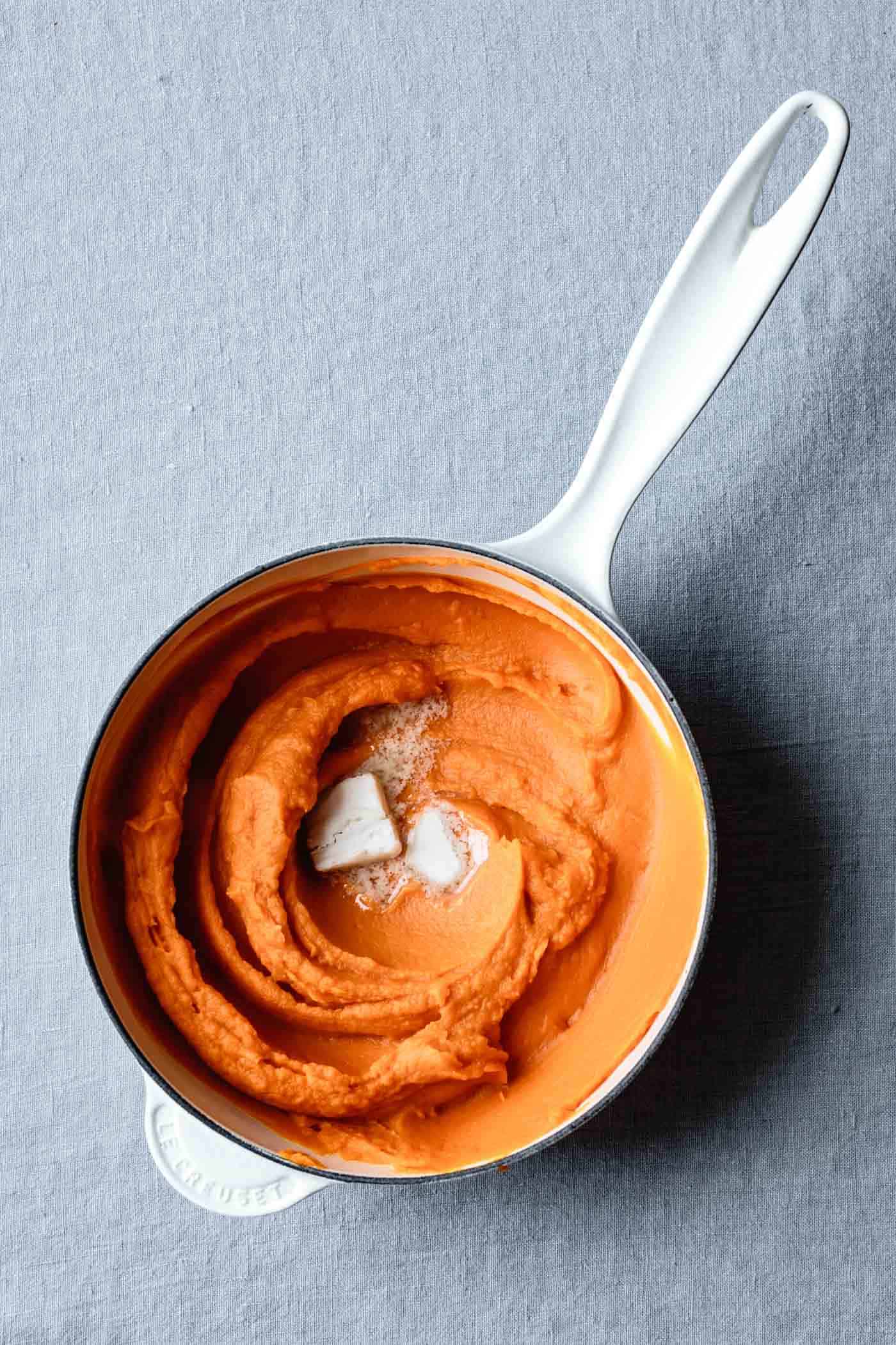 silky sweet potato puree is swirled in a saucepan with melty butter