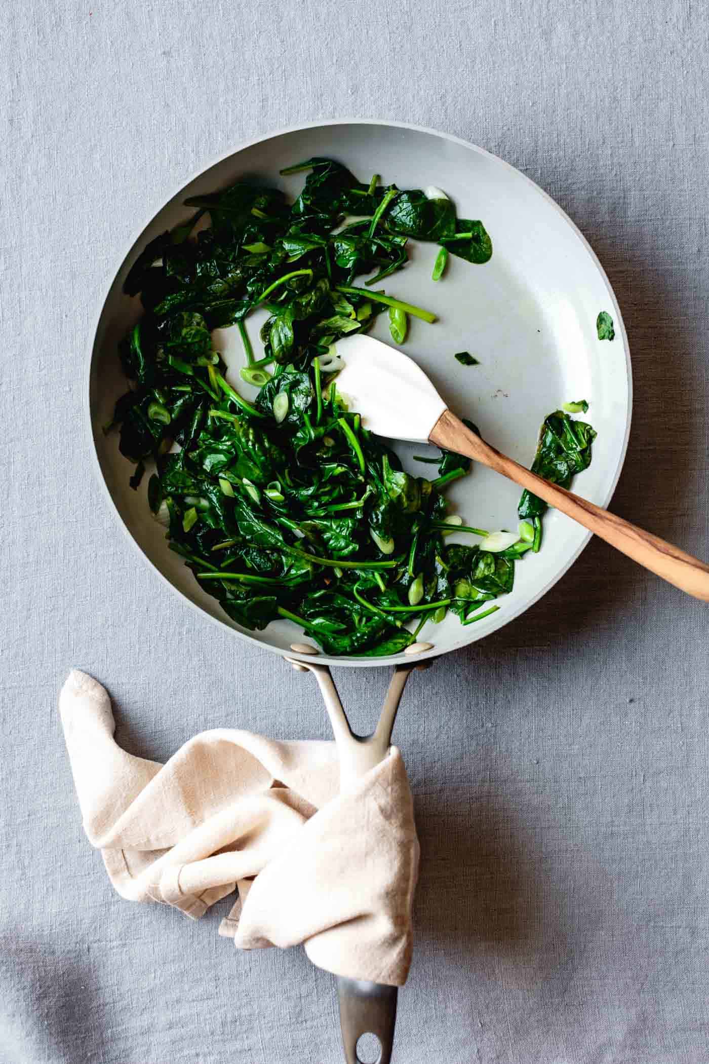 spinach and scallions have been wilted in a skillet